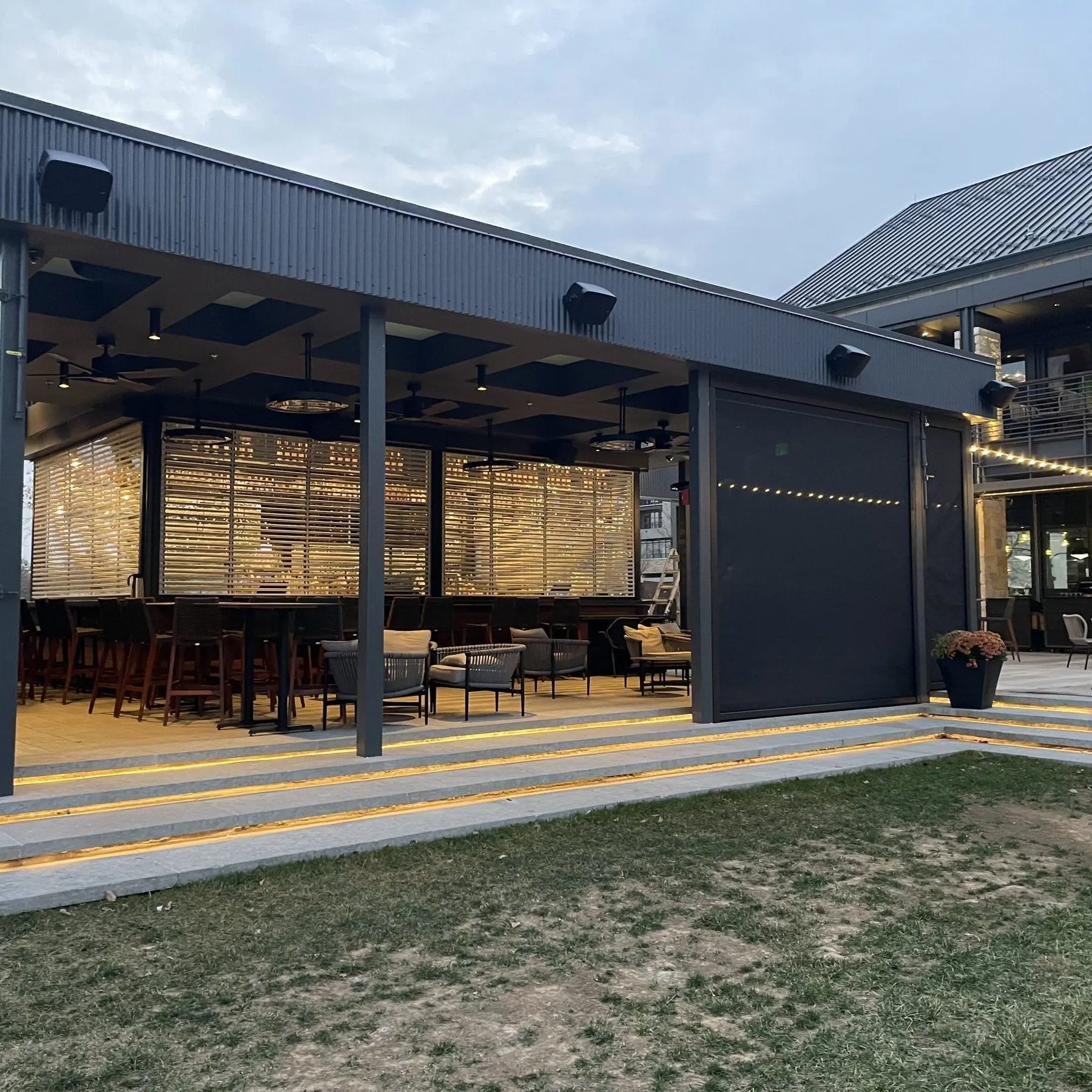 Restaurant patio with a dark screen lowered beside open seating