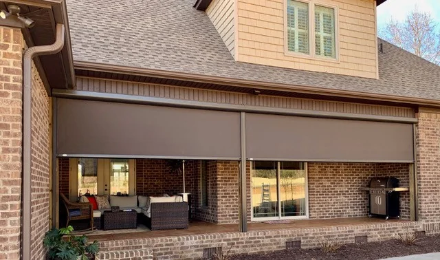 Covered brick patio with brown motorized shades lowered for sun and privacy control