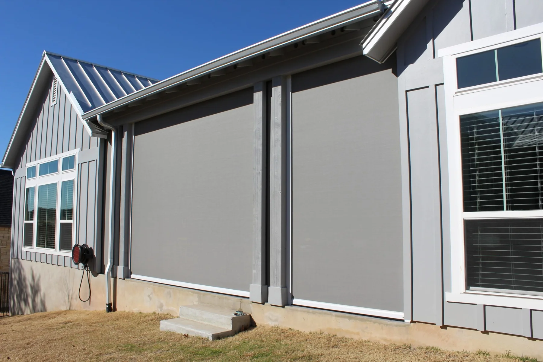 Gray home exterior with large motorized solar patio shades
