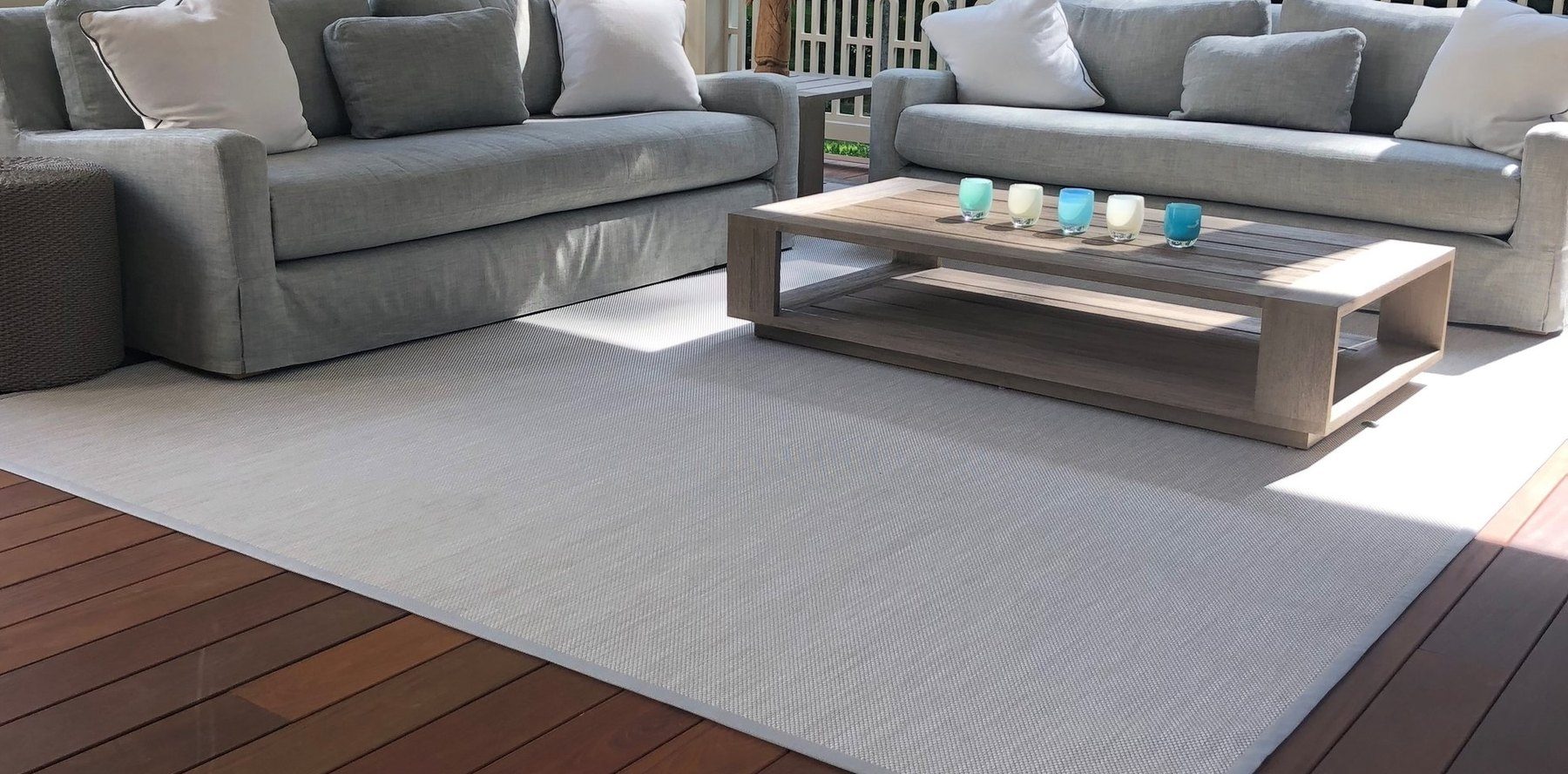 Light Infinity outdoor rug beneath gray sofas and wood coffee table on a deck