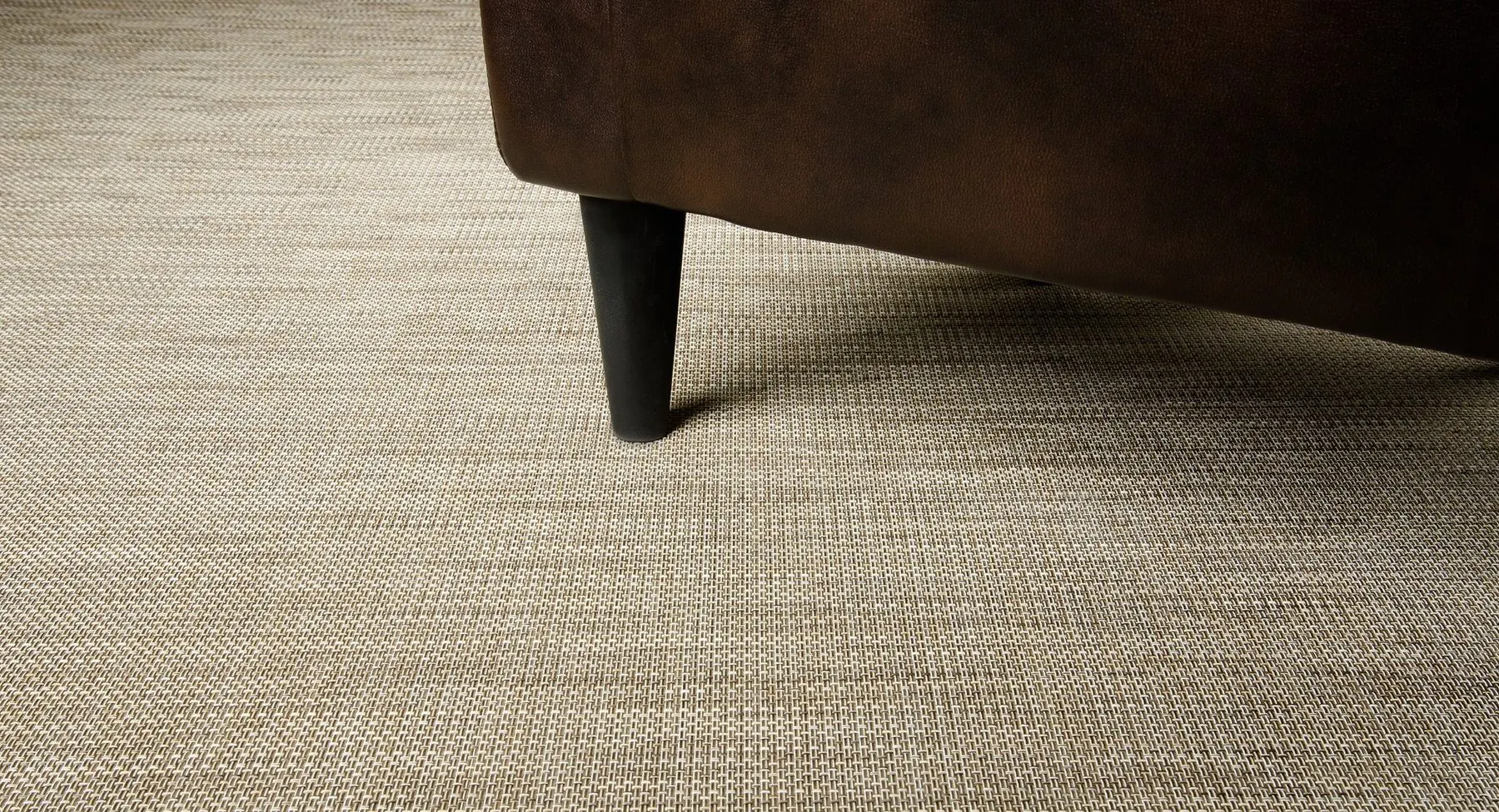 Closeup of woven vinyl Infinity rug texture under a furniture leg