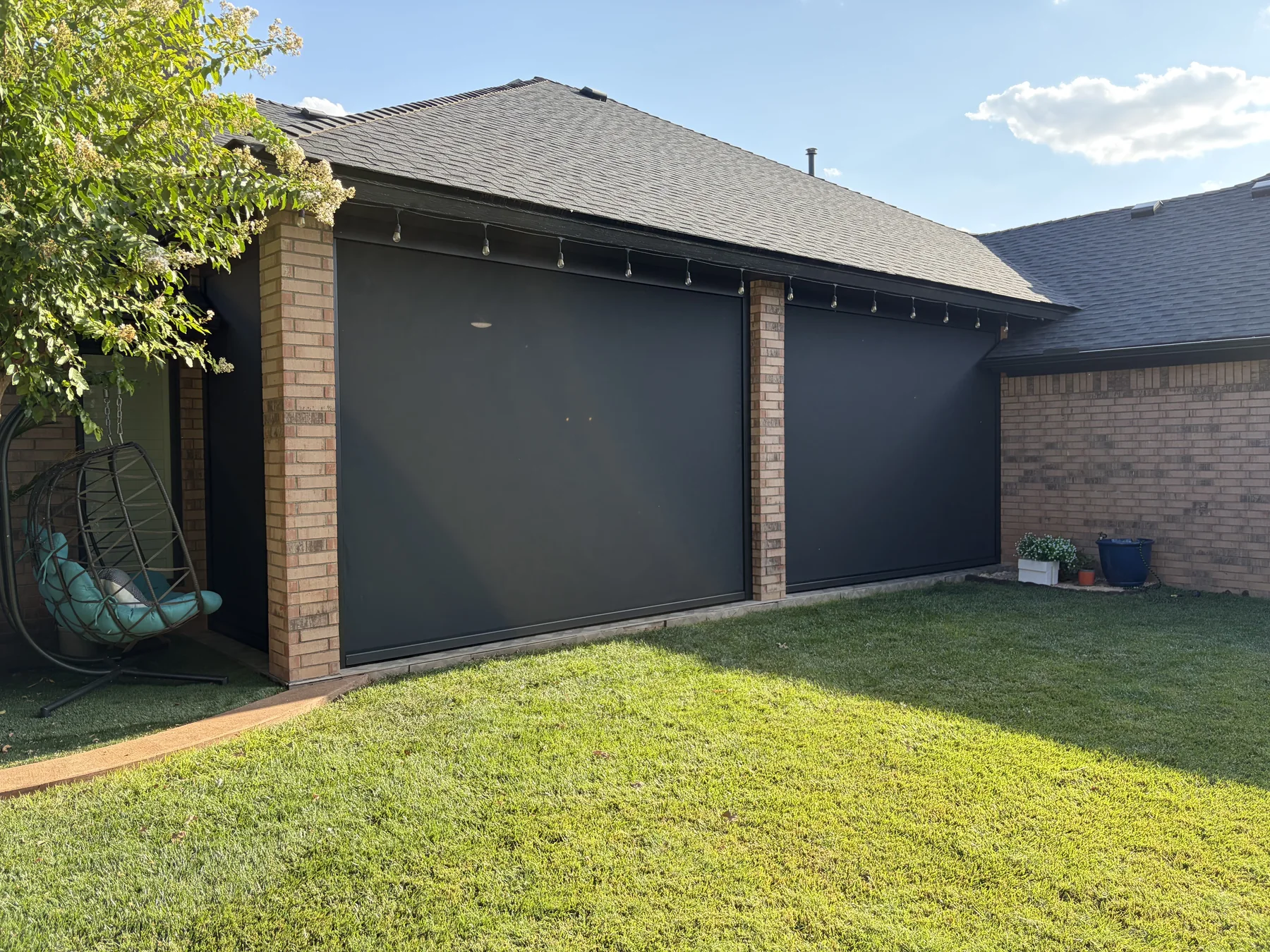Two professionally installed motorized patio shades enclosing a covered residential patio