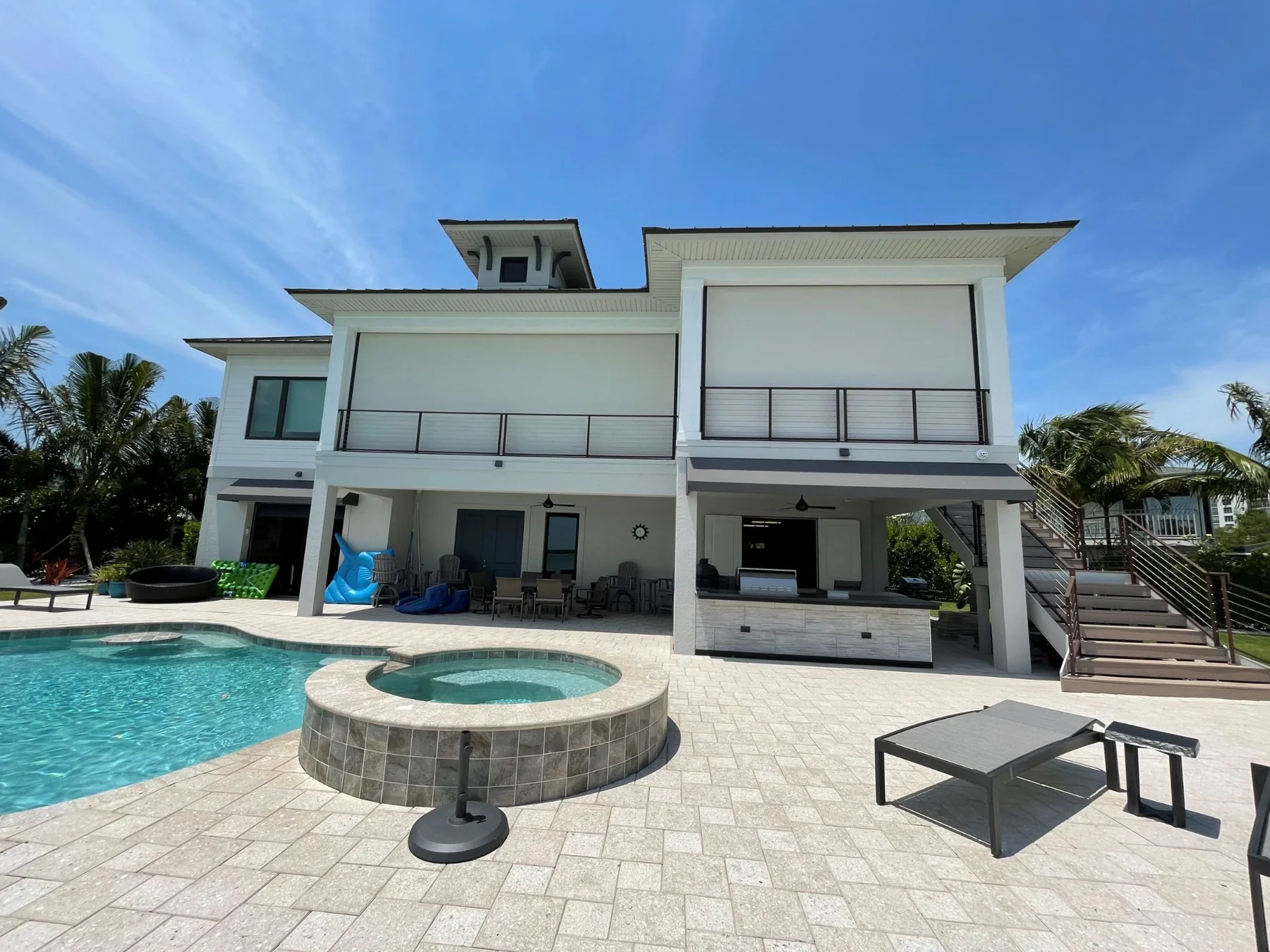 White luxury pool patio with large exterior motorized shades